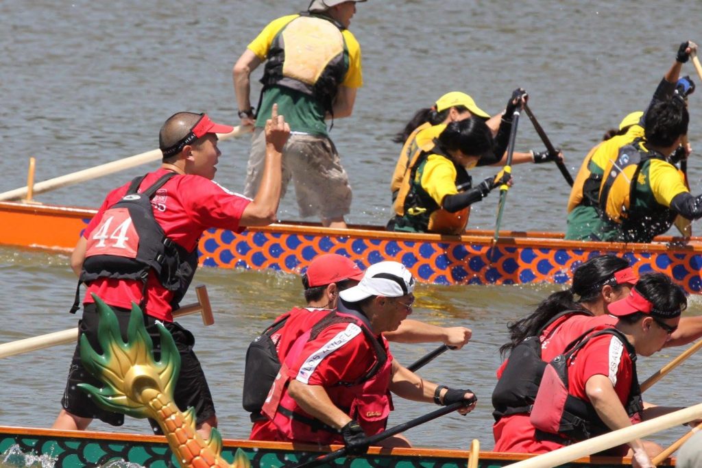 people rowing and racing dragonboats on water